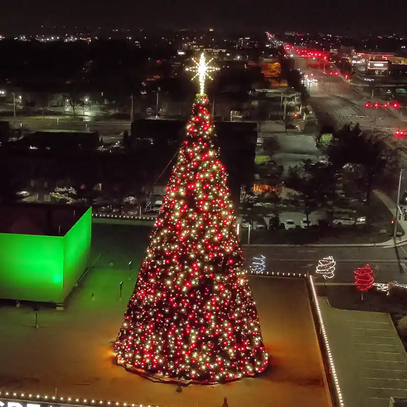 38-foot commercial Christmas panel tree with red and warm white lights installed outdoors at night