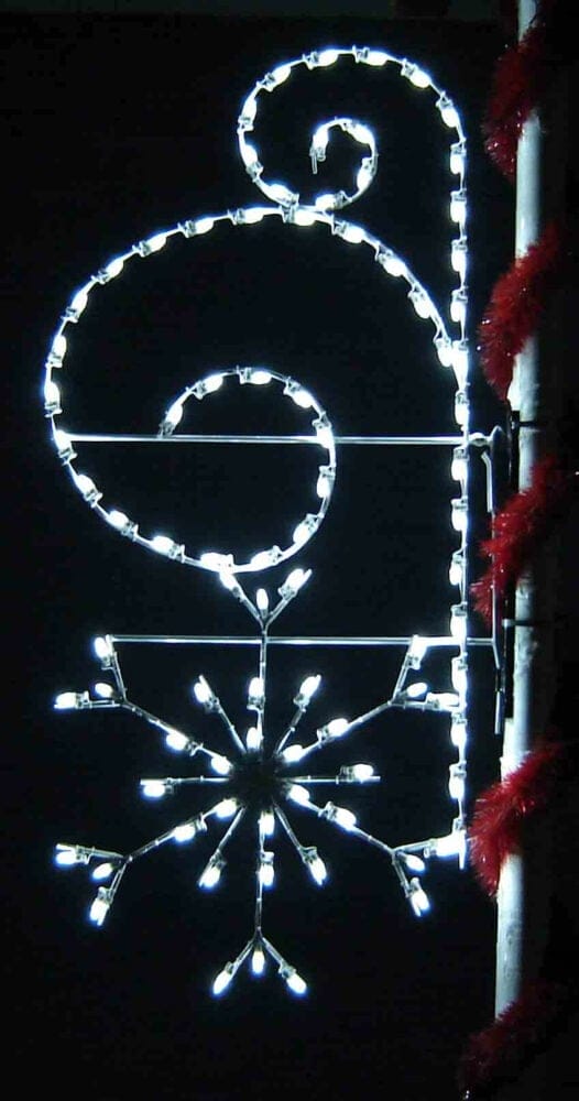 8-foot snowflake with scroll pole mount holiday light display illuminated on a decorated pole at night