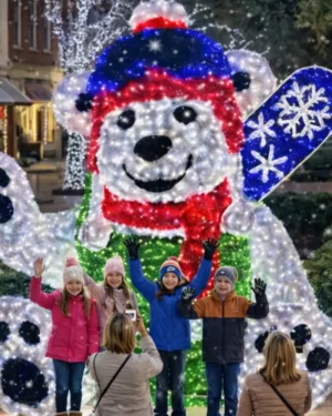 Children posing before illuminated polar bear holiday display
