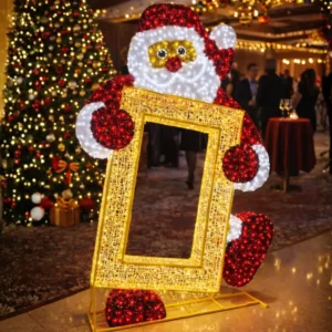 Illuminated Santa holding golden frame near Christmas tree