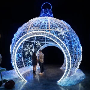 Couple inside giant illuminated Christmas ornament display