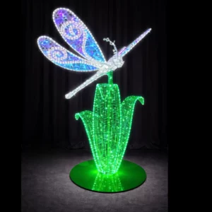 Illuminated dragonfly sculpture on glowing green plant