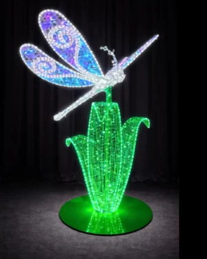 Illuminated dragonfly sculpture on glowing green plant
