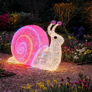 Glowing snail sculpture in flower garden at night