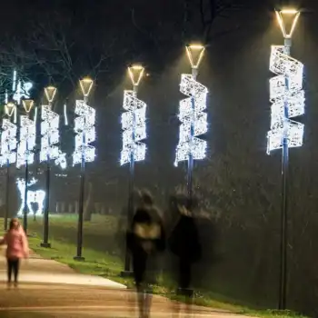 People walking under illuminated park light pole decorations
