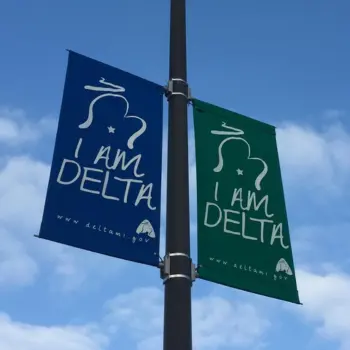 Blue and green I Am Delta year round commercial street banners on lamppost