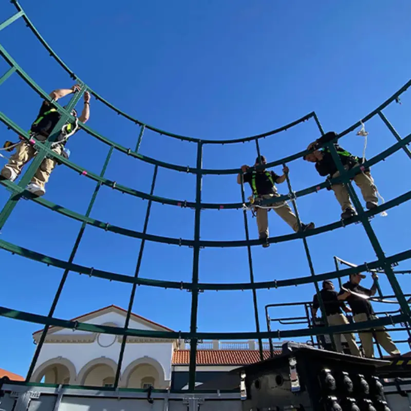 Workers installing lights on large curved metal framework