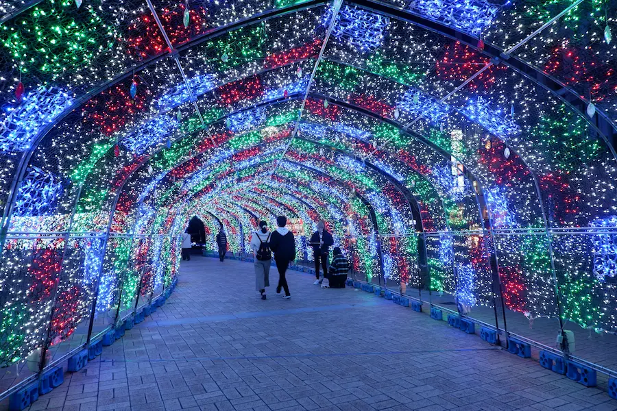 Visitors walking through an immersive Christmas light tunnel display