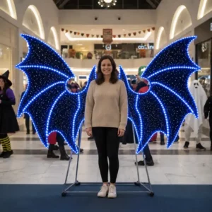 Woman posing with glowing blue bat wings commercial Halloween light display
