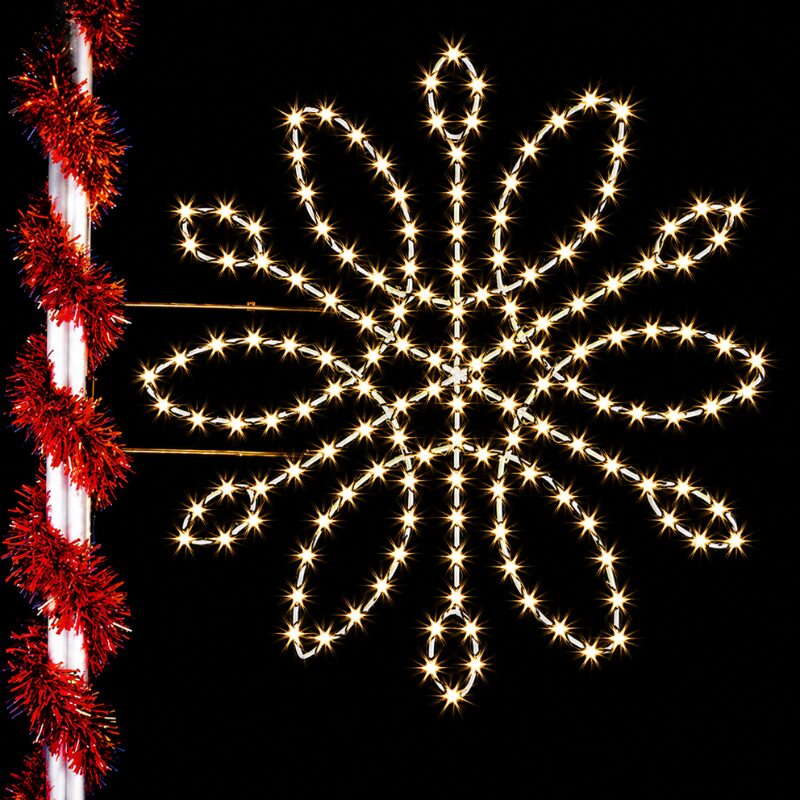 Illuminated snowflake light decoration on pole at night