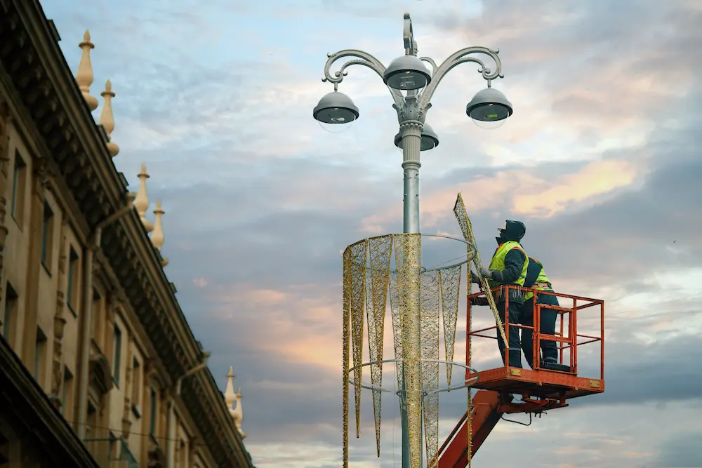 City crew installing commercial Christmas lights along a downtown street