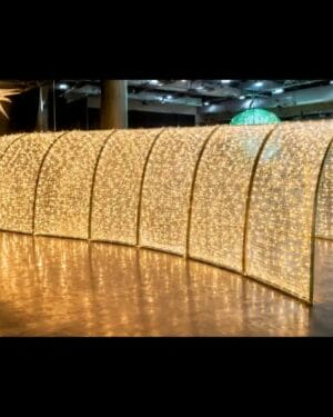 Illuminated tunnel of warm white string lights indoors