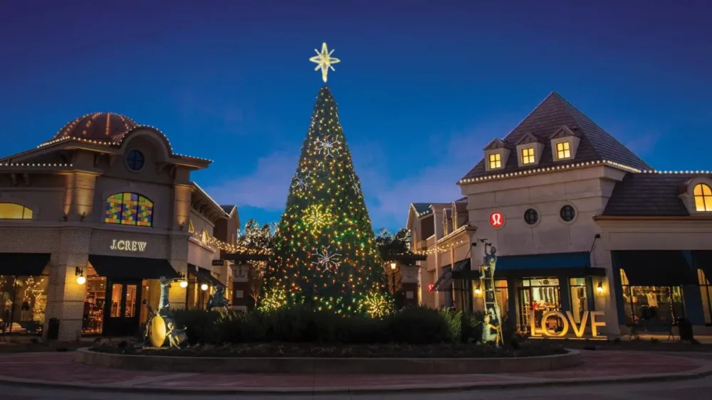 Illuminated Christmas tree in outdoor shopping center at dusk
