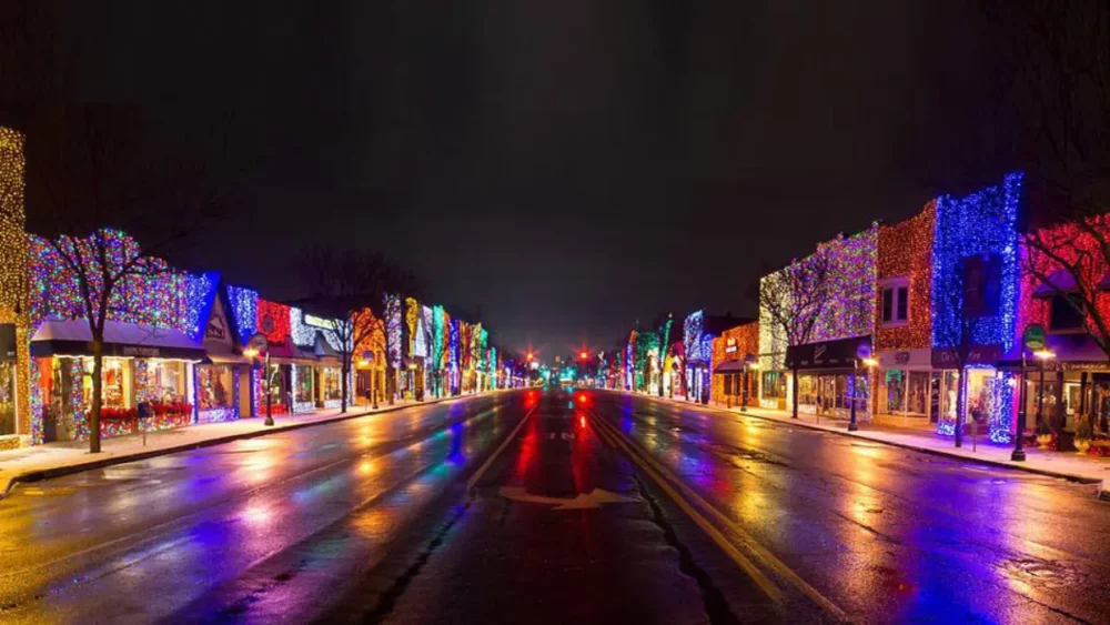 Rainy downtown street glowing with colorful commercial holiday lights