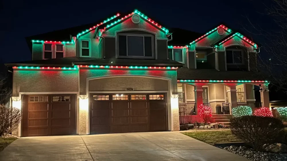 House decorated with red and green Christmas lights at night