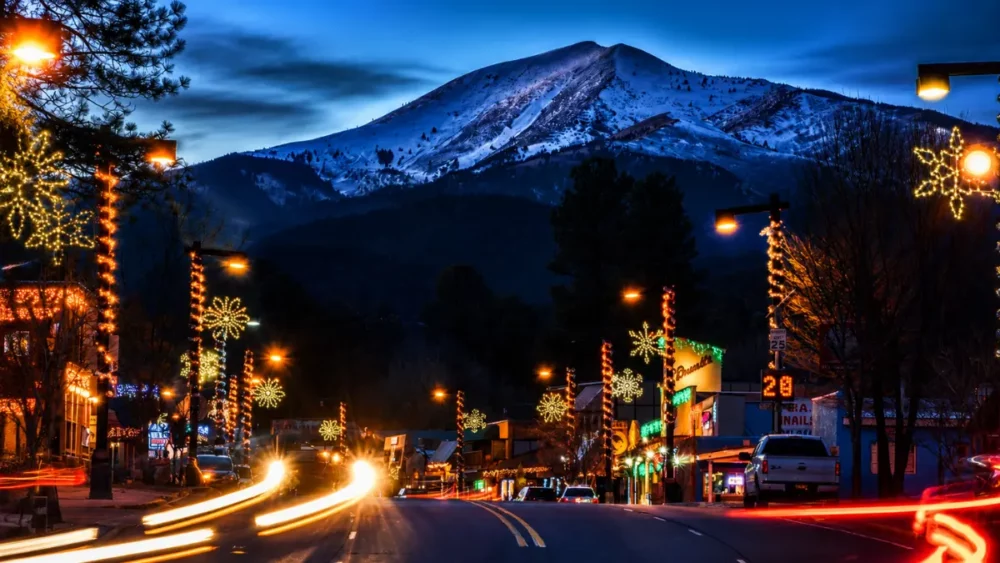 Snowy mountain above festive downtown street at dusk